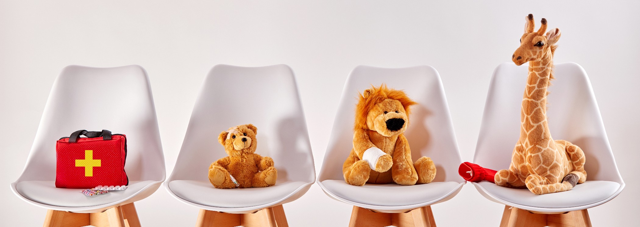 Three cute stuffed animal toys on chairs in the waiting room of a modern hospital or health center for children